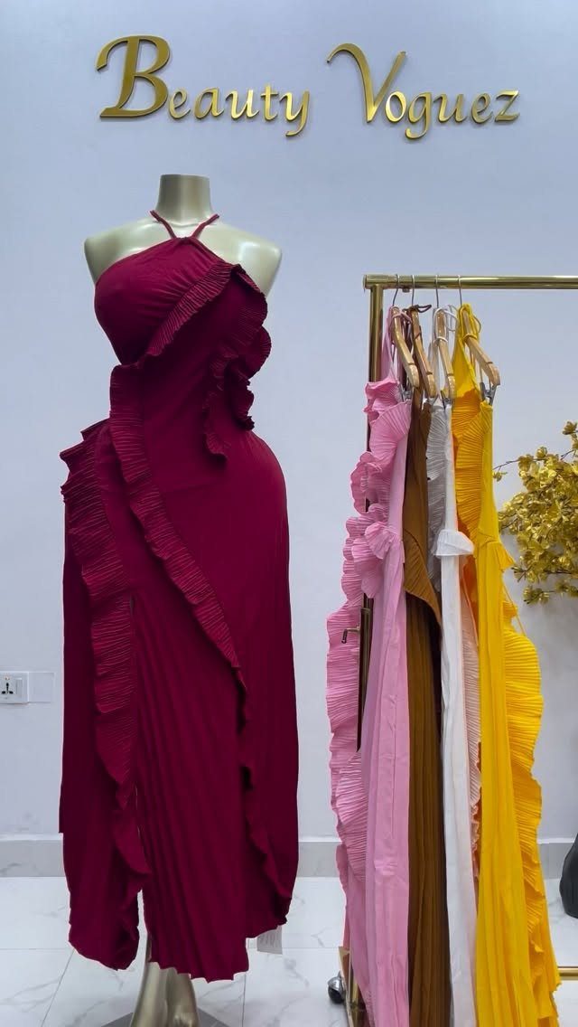 Maroon ruffled halter maxi dress on a mannequin with colorful dresses on a rack.