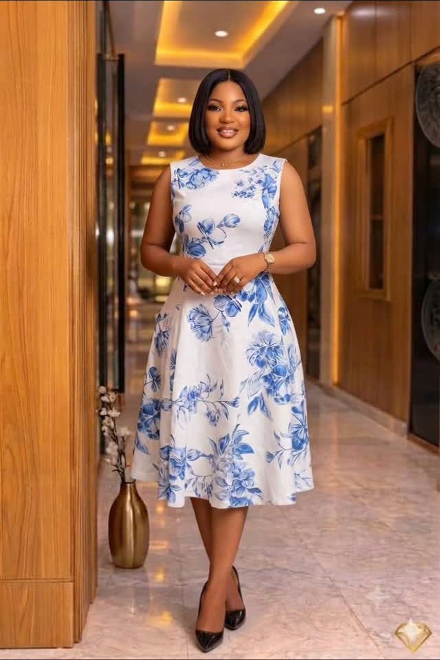 Woman in a white and blue floral A-line dress and black heels.