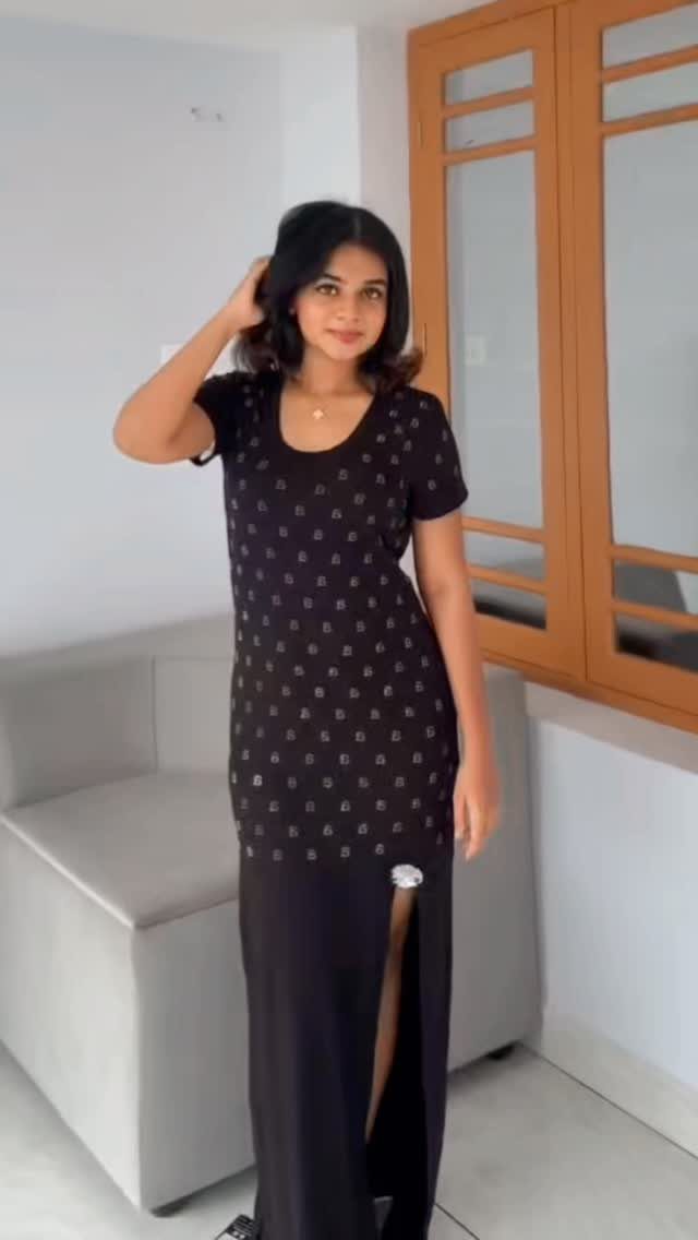 Woman wearing a long black patterned maxi dress with a high side slit.