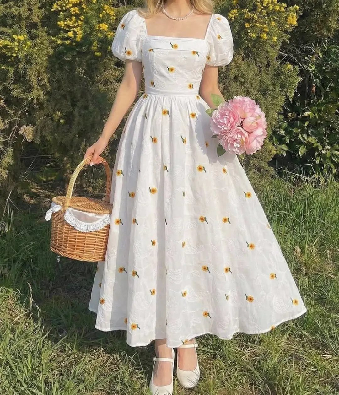 Woman in a white floral sundress holding a wicker basket and pink roses.