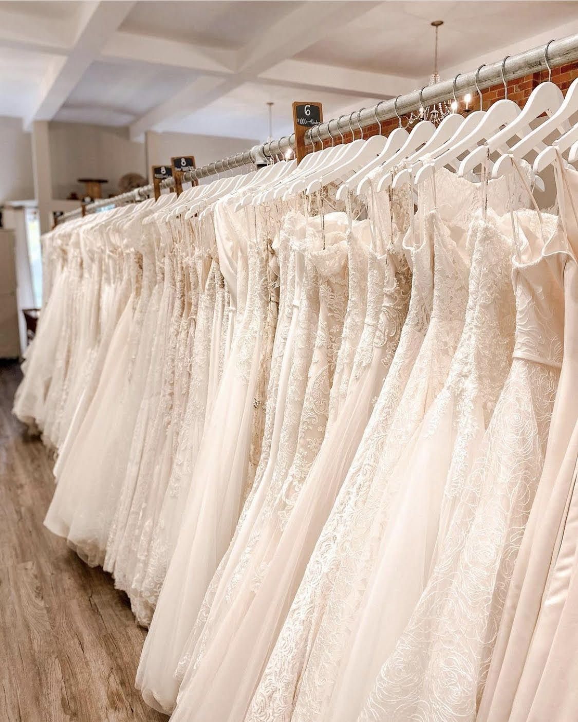 Row of white wedding dresses hanging on a rack in a bridal boutique.