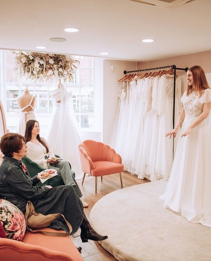 Woman wearing a wedding dress standing in a private bridal boutique suite.