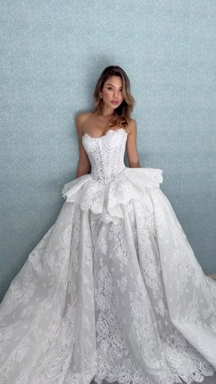 Woman in a strapless white lace wedding gown with a voluminous skirt.