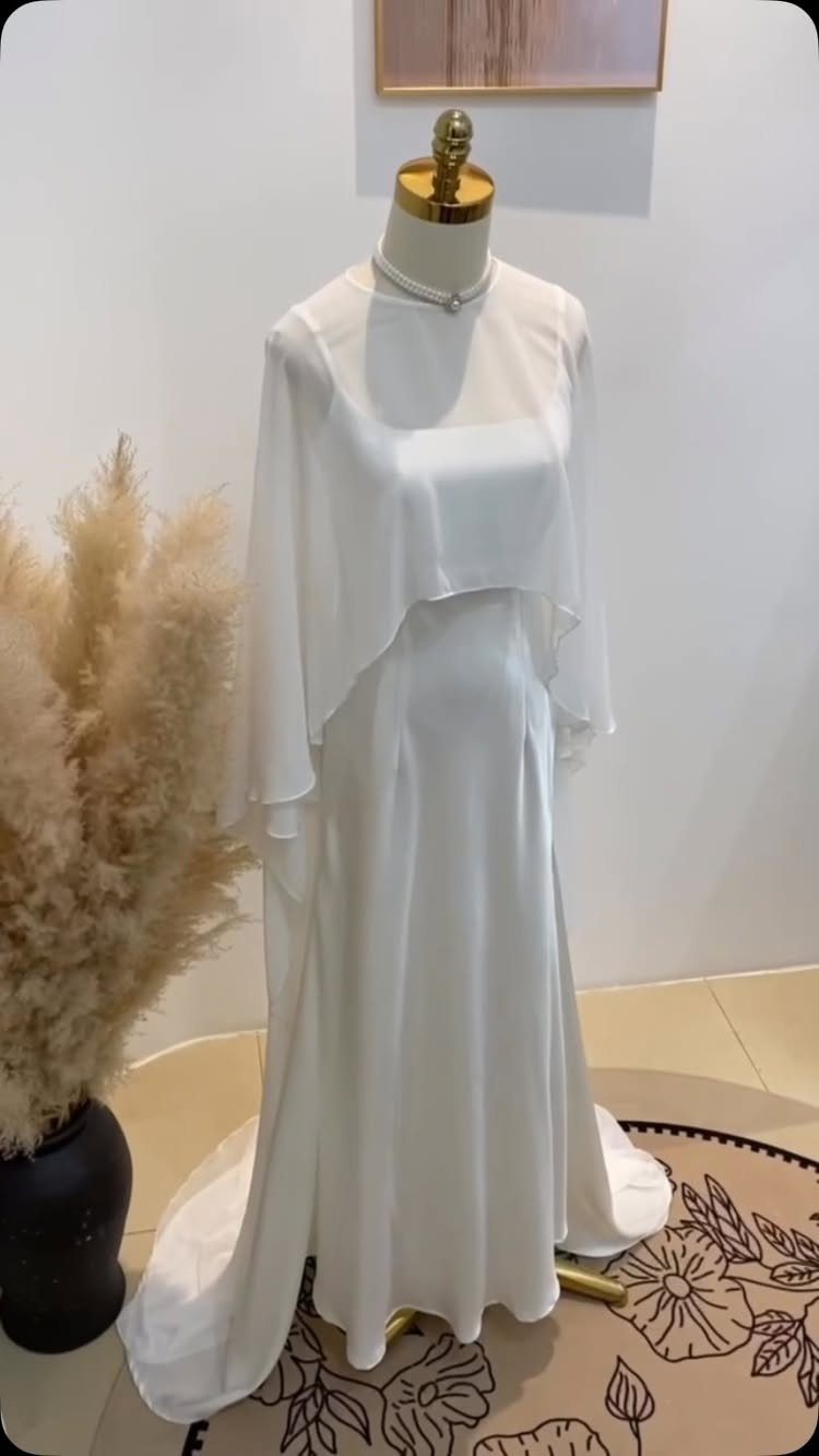 White wedding gown with sheer chiffon overlay and satin skirt on a mannequin.
