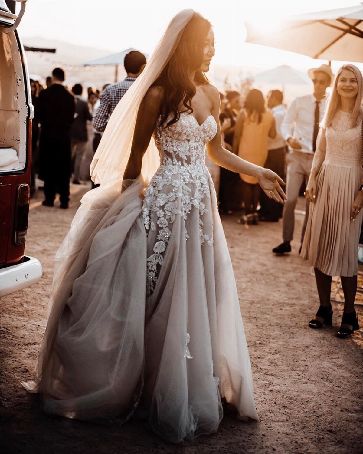 Woman in a floral lace wedding gown with a voluminous tulle skirt and veil.