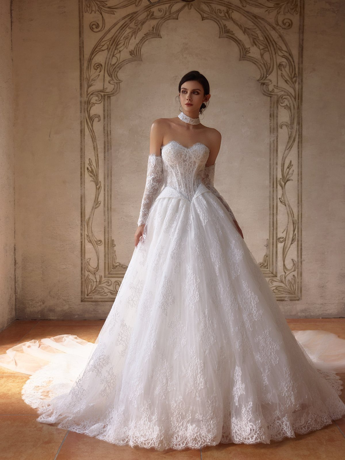 Woman in a white lace wedding gown with a sculpted bodice and detachable sleeves.