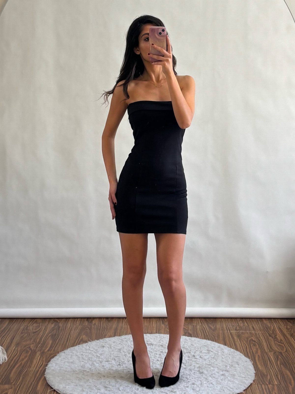 10 Zara Party Dresses to Wear This Season 5 Woman wearing a black strapless mini dress and black high heels in a studio.